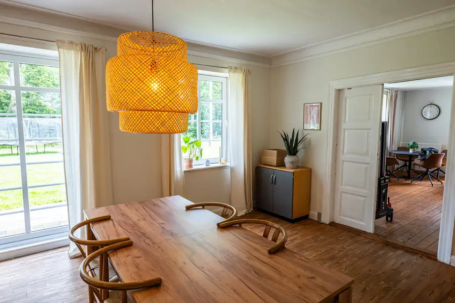 Fællesrummet på Faurholt med spisebord, pendel og døren ud til resten af huset