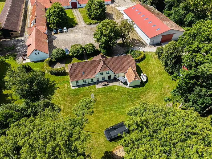 Luftfoto af Faurholt med hovedhus, længer og græsarealer omgivet af træer