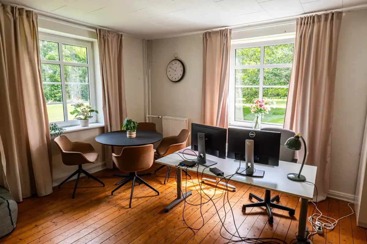Arbejdsrum på Faurholt med bord, skærme og vinduer ud mod markerne