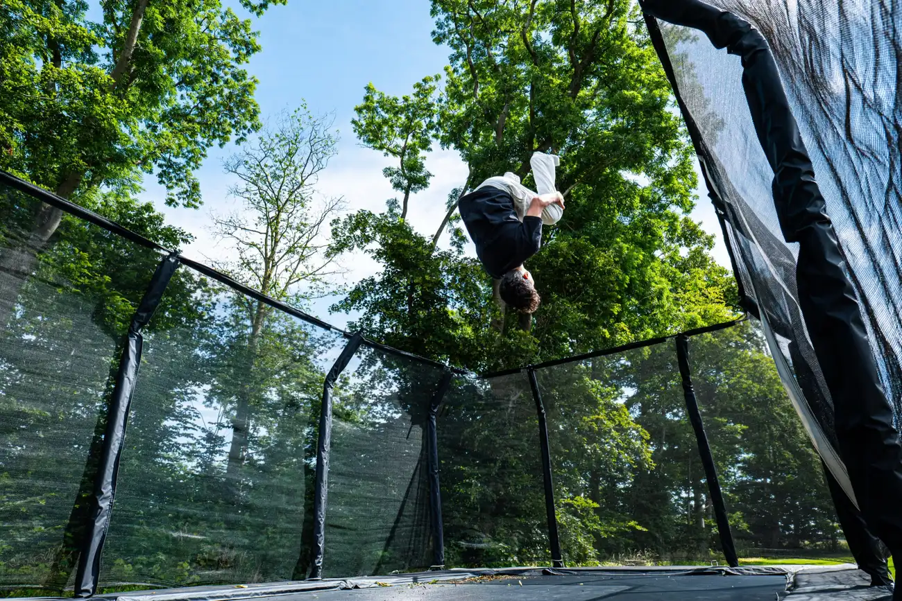 Trampolin i haven på Faurholt med træerne omkring